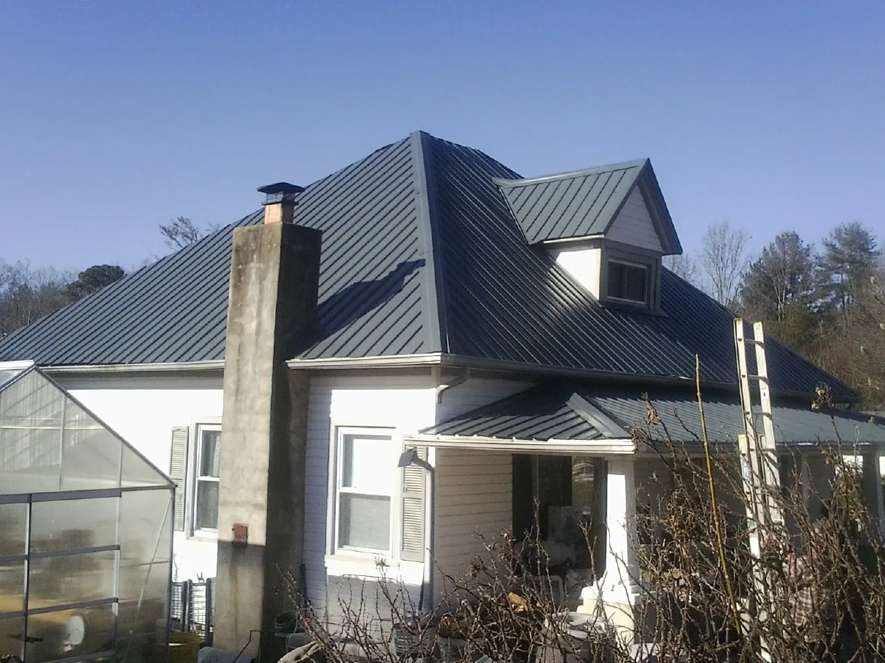 Dark blue standing seam metal roof on a white farmhouse with dormer — Slate & Tile Roof Repair by Roofing Brothers in New Holland
