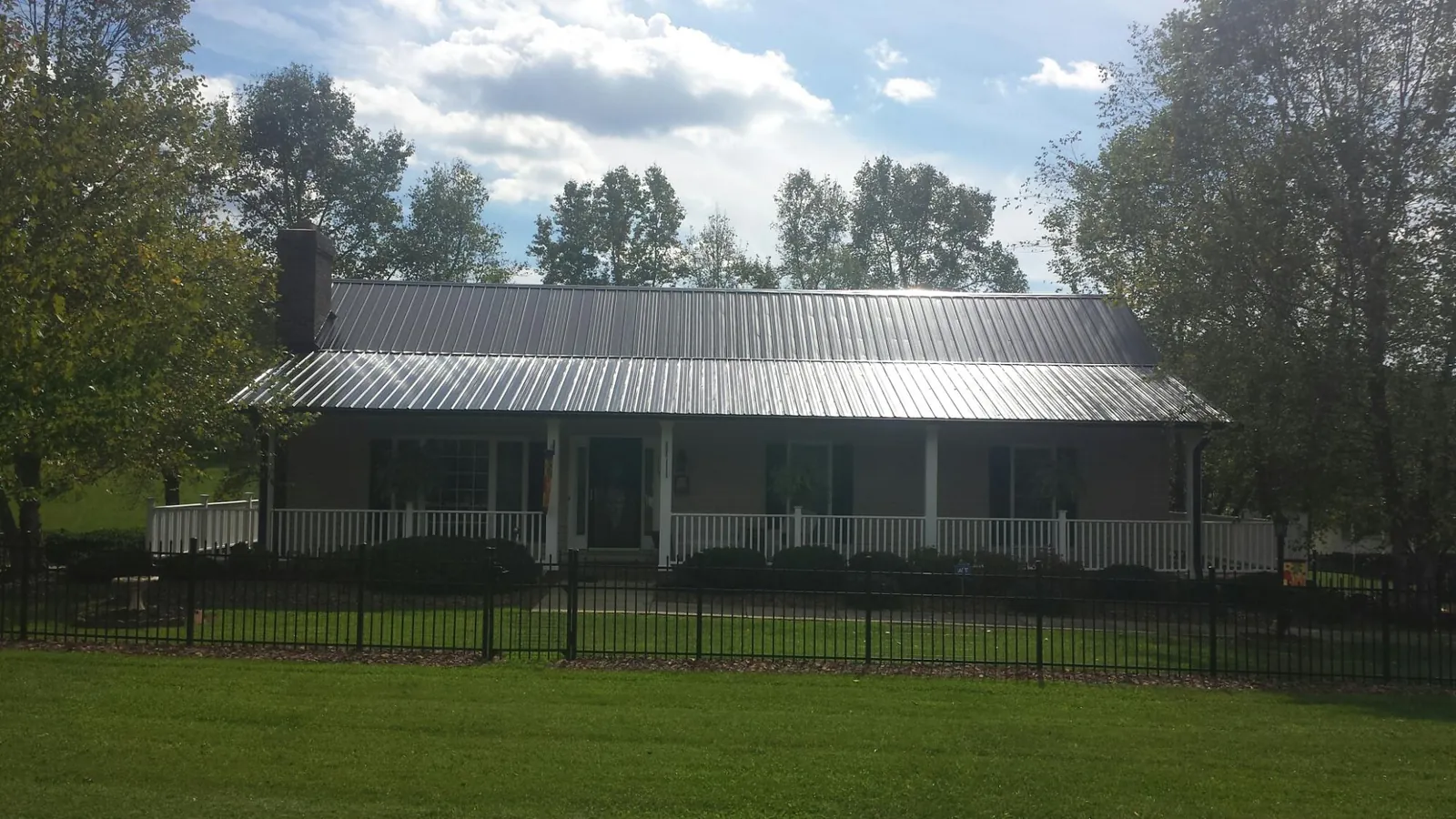Gray metal roof on a brick ranch with a full width front porch — Gutter Guard Installation work by our crew in New Holland