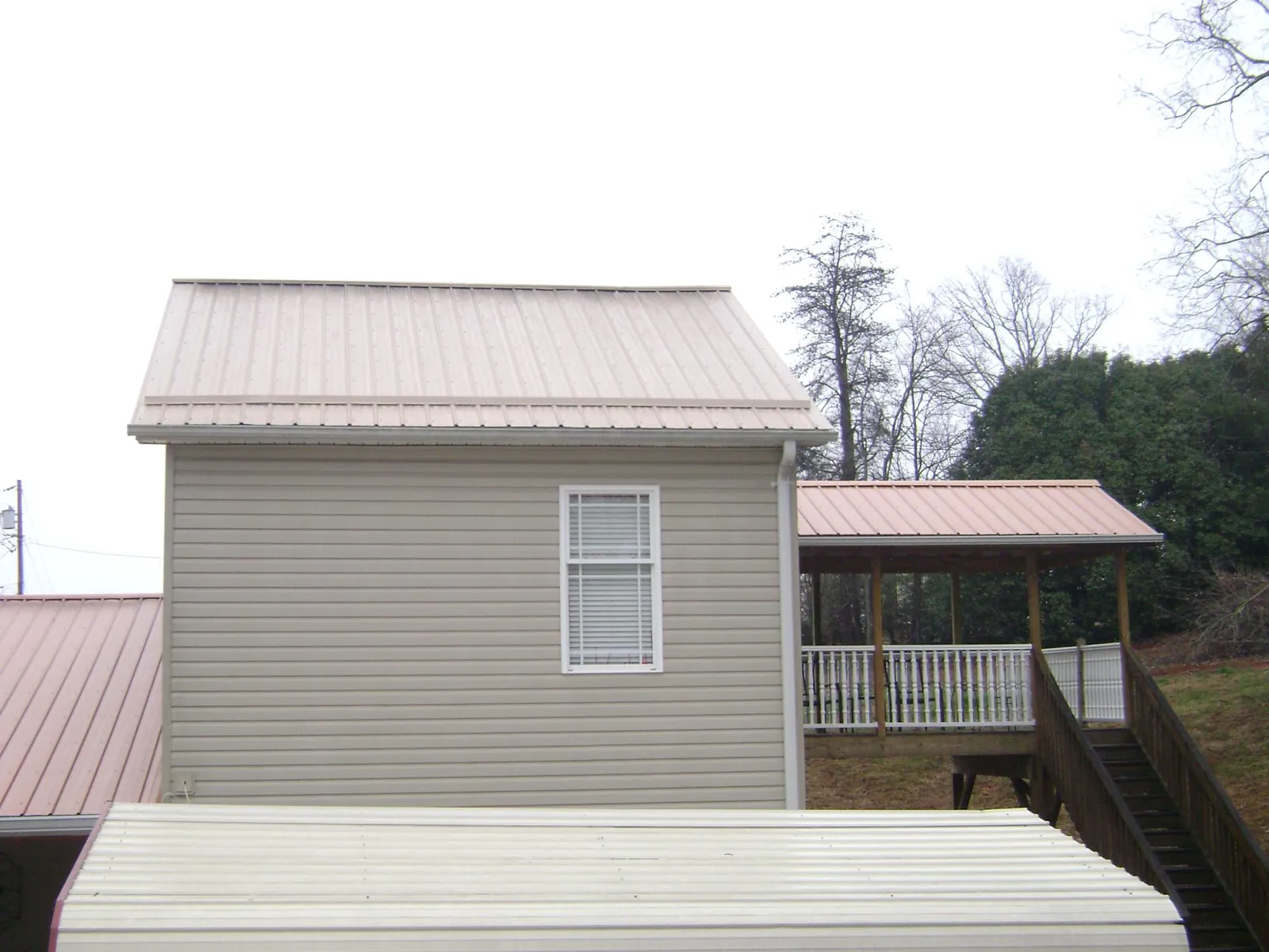 Tan metal roofs on a two story addition and attached porch, from a Roof Replacement job in New Holland