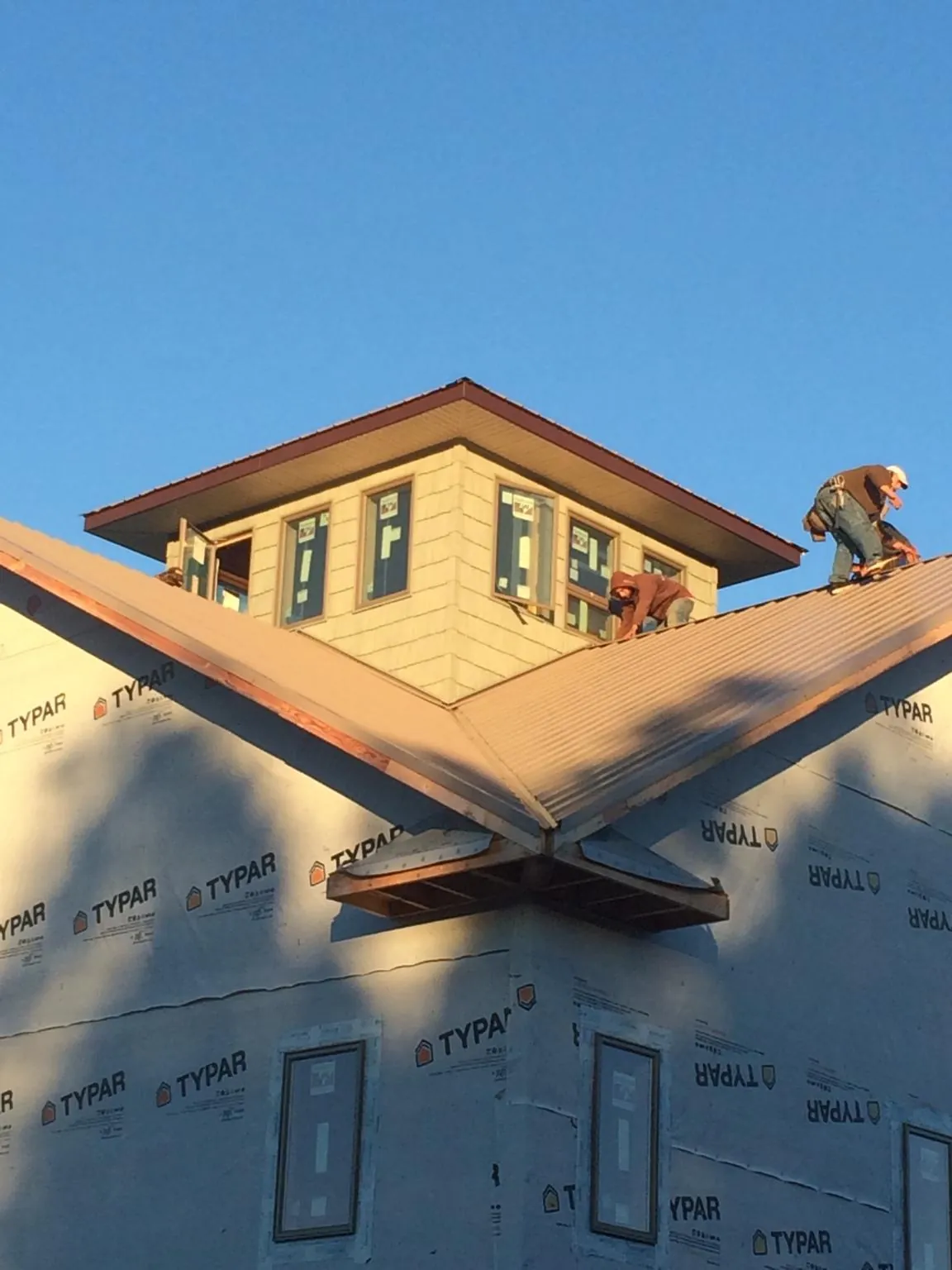 Roofers working around a rooftop cupola on a new metal roof at sunset — Roof Waterproofing in New Holland by Roofing Brothers